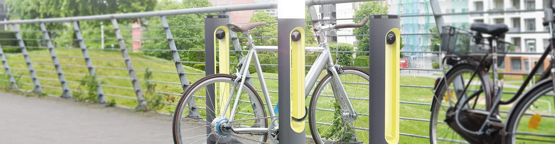 SMARTPOLE-Ladestationen entlang eines Brückengeländers mit geparkten Fahrrädern im urbanen Umfeld