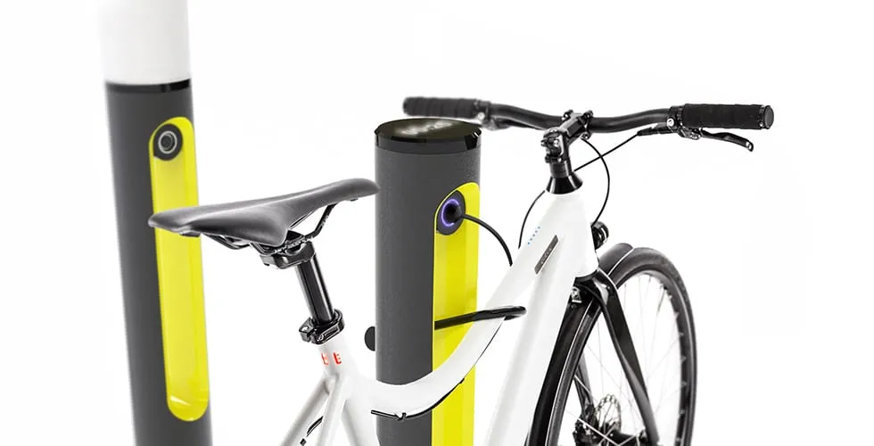 Weißes E-Bike geparkt und angeschlossen an eine SMARTPOLE-Ladestation mit weiteren Masten im Hintergrund