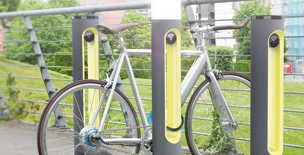Zwei SMARTPOLE-Ladestationen an einem Brückengeländer mit geparkten Fahrrädern im urbanen Umfeld