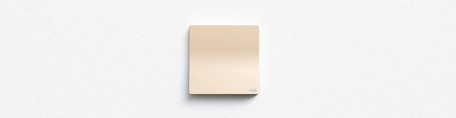 Einzelner ABB XUAN ZHI Schalter in Champagnergold, zentriert auf texturierter hellgrauer Wand, minimale Rahmung